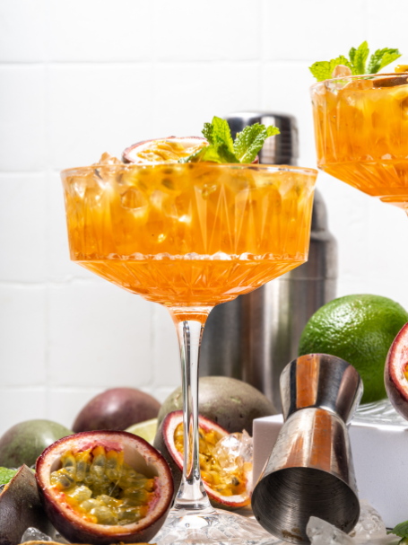 Cocktail pornstar martini, composé de vodka, de nectar de maracuja, de sirop de vanille et de jus de citron vert, servi dans un verre garni d'un demi fruit de la passion pour une touche exotique.