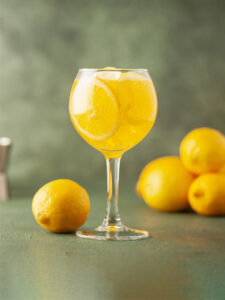 Cocktail Limoncello Spritz jaune servi dans un verre piscine, préparé avec du limoncello, du prosecco et de l’eau pétillante.