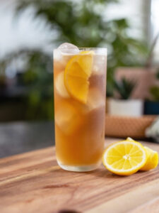 Cocktail Long Island Iced Tea, servi dans un verre long drink et garni d'une demie-rondelle de citron jaune.
