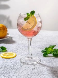 cocktail gin pink dans un verre piscine avec des fraises et des rondelles de citron vert