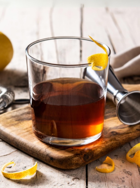 Cocktail Sazerac à base d'absinthe et de cognac servi dans un verre old fashioned et décoré d'un zeste de citron jaune