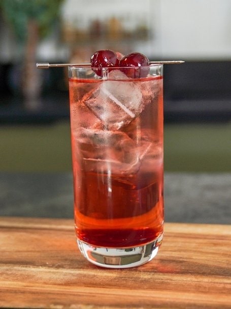 cocktail sans alcool Shirley Temple, à base de ginger ale, limonade et sirop de grenadine de couleur rose et rouge avec une cerise sur le dessus.
