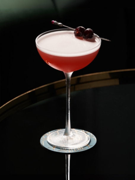 Cocktail Mary Pickford, servi dans un verre à cocktail, décoré de deux cerises au marasquin.