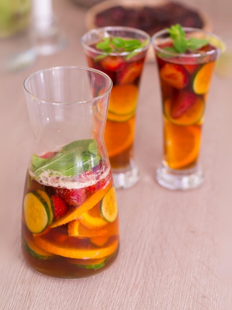 Cocktail Pimm's avec triple sec, limonade, menthe fraîche, tranches de concombre, rondelles d'orange et de citron vert, et une tranche de fraise.