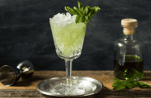 Cocktail avec de l'absinthe servi dans un verre décoré avec de la glace pilée et des feuilles de menthe