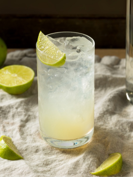 Cocktail Gin Rickey, dans un verre highball garni d'un quartier de citron vert.
