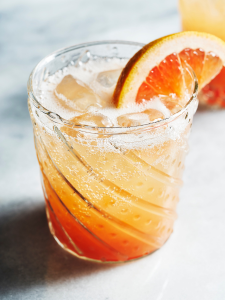 Cocktail Paloma avec de la Tequila et de la limonade au pamplemousse servi dans un verre décoré avec du pamplemousse.