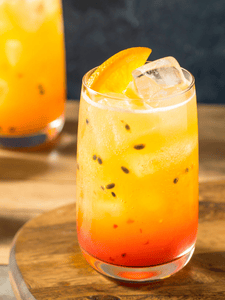 cocktail sans alcool avec jus d'orange, jus de fruit de la passion et grenadine servi dans un verre décoré avec une tranche d'orange