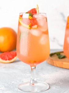 Cocktail Spritz avec jus de passion et pamplemousse, sans alcool, servi dans un verre décoré avec une tranche de pamplemousse