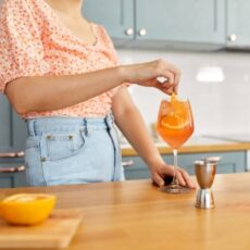 Une femme en train de préparer un Apérol Spritz.