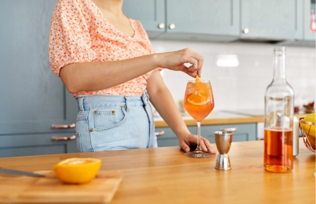 Une femme en train de préparer un Apérol Spritz.