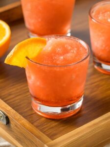 cocktail frozen negroni dans un verre old fashioned. Le verre est rempli d'un negroni granité servi avec un quartier d'orange sur le dessus.