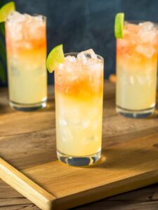 cocktail lemon lime and bitters dans un verre highball avec une belle couleur dégradé orange et jaune pétillante avec une demi rondelle de citron vert sur le dessus en décoration