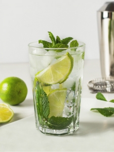 cocktail mojito servi dans un verre à cocktail avec des quartiers de citron vert, de la menthe et des glaçons