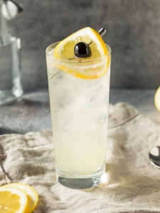 Cocktail collins, présenté dans un verre long drink décoré d'une rondelle de citron et d'une cerise confite.