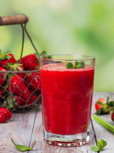 smoothie à la fraise, framboise et menthe décoré avec des feuilles de menthe sur le verre