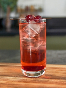 Cocktail sans alcool Shirley Temple, dans un verre long drink rempli de glaçons et décoré d'une cerise au marasquin.