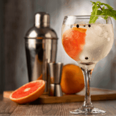 Cocktail gin tonic : variante du cocktail avec du pamplemousse et des feuilles de menthe en décoration sur le verre.