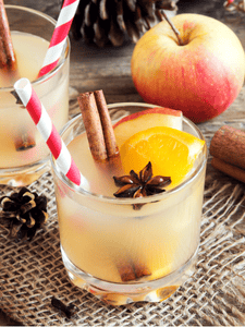 cocktail punch avec du jus de pomme, poire, orange, décoré avec un bâton de cannelle et un quartier d'orange