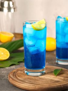 Cocktail Blue Lagoon sans alcool servi dans un verre long drink transparent, rempli d’un mélange bleu éclatant à base de jus de pamplemousse, limonade pétillante et sirop de menthe, décoré d’une rondelle de citron et de glaçons