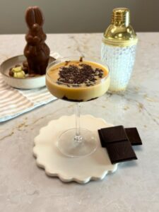 Cocktail Chocolate Martini, à base de vodka, baileys et crème de cacao. Servi dans un verre à cocktail, parsemé de copaux de chocolat.