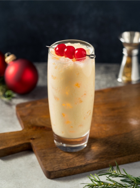 Cocktail Snowball, une recette à base d'advocaat, de limonade et de jus de citron vert, servie dans un verre long drink décoré de trois cerises confites.