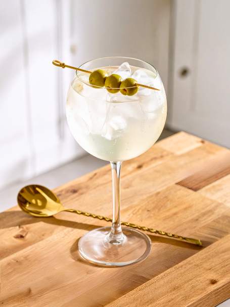 cocktail spritz bergamote servi dans un verre ballon avec des glaçons avec des olives en décoration sur le verre