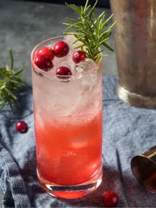 Cocktail sans alcool avec de la limonade et du Cranberry servi dans un verre décoré avec une branche de thym frais