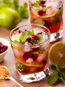 cocktail mojito cranberry avec rhum blanc et jus de cranberry servi dans un verre avec des glaçons et feuilles de menthe