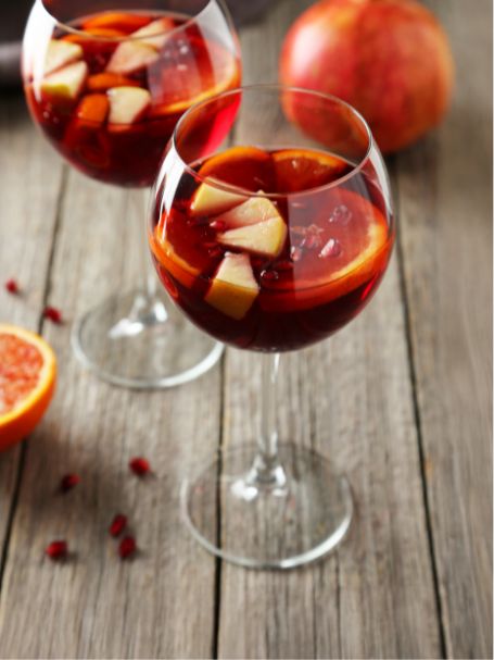 Cocktail sangria sans alcool avec du jus de raisin rouge, servi dans un verre avec des morceaux d'oranges et des glaçons