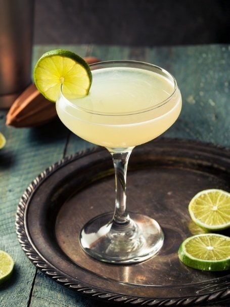 Cocktail sans alcool Virgin Daiquiri à base de rhum désalcoolisée, de jus de citron vert et de sirop de canne, dans un verre à cocktail avec une tranche de citron vert sur le rebord du verre.