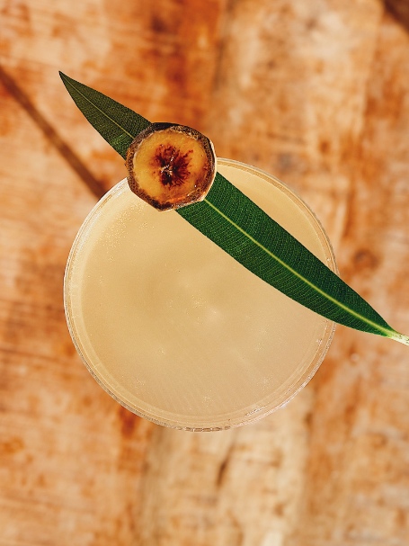 Cocktail Lagoon, à la Clairette de Die, servi dans un verre à pied et décoré d'une rondelle de banane flambée.