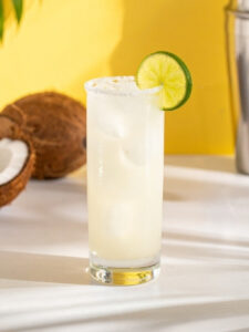Cocktail Caipi-coco, dans un verre long drink, à base de cachaça, de lait de coco et de sirop de canne. Avec une rondelle de citron vert en décoration.
