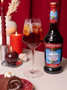 Cocktail Spritz Cassis à la Française par l'Héritier-Guyot, à base de crème de cassis, de crémant et d'eau gazeuse, dans un verre ballon.