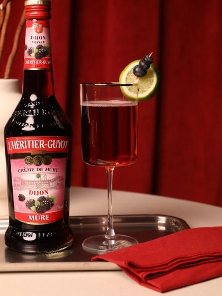Cocktail Spritz Mûre à la Française par L'Héritier-Guyot, à base de crème de mûre, de crémant et d'eau gazeuse, dans un verre piscine.