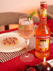 Cocktail Spritz Pêche à la Française par L'Héritier Guyot, à base de crème de pêche, de crèmant rosé et d'eau gazeuse, dans un verre piscine.