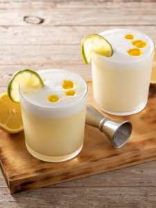 cocktail sour au pisco et au citron servi dans un verre old fashioned avec de la mousse sur le dessus et une rondelle de citron vert.