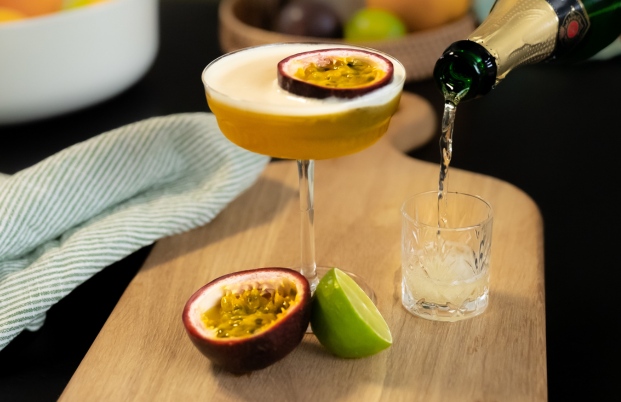 Cocktail Porn Star Martini, servi dans un verre à pied et décoré d'une moitié de fruit de la passion. Le cocktail est accompagné d'un shot de vin pétillant.