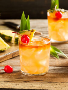 Cocktail Virgin Mai Tai sans alcool à base d’ananas, servi avec glaçons, cerises et morceaux d’ananas frais. Boisson tropicale rafraîchissante idéale pour un apéritif d’été, une réception ou un bar à cocktails sans alcool.